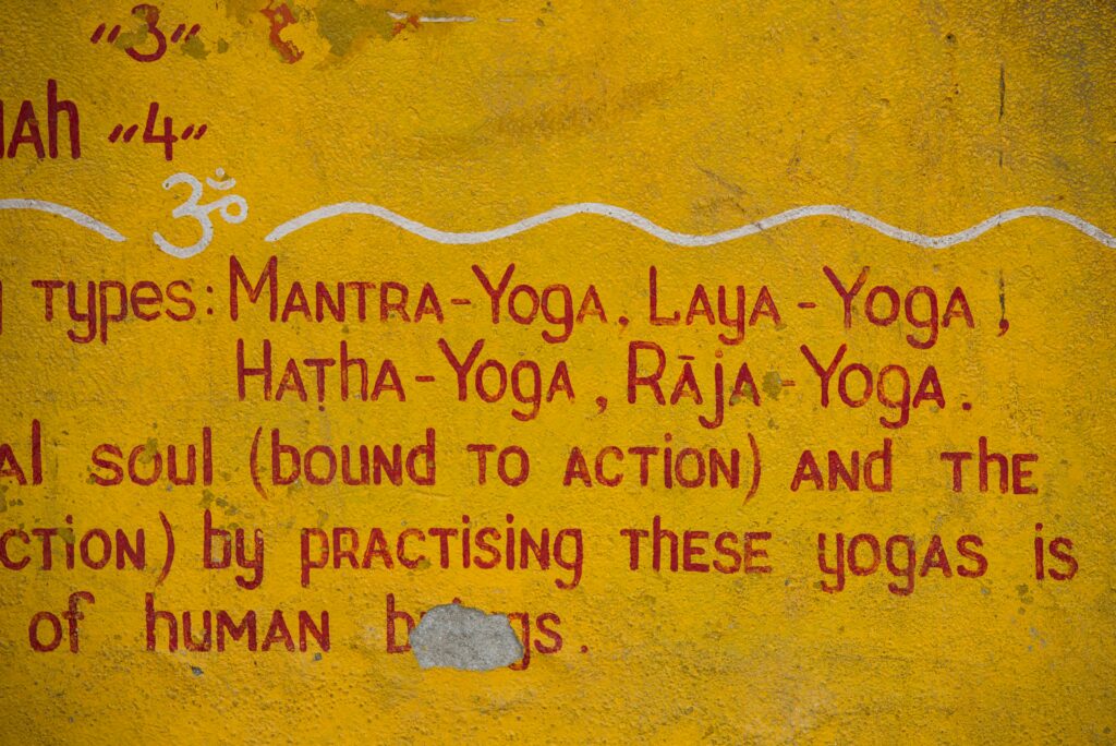Auf eine gelbe Wand gemalt: die Namen der Yogawege — Mantra-Yoga, Laya-Yoga, Hatha-Yoga, Raja-Yoga